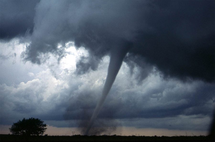 A large tornado beneath a dark storm cloud over open plains